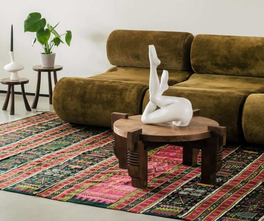 Anissa Kermiche white leg sculpture on a wooden table in front of a velvet sofa